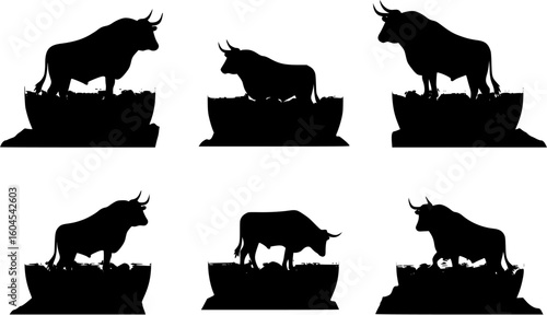 Silhouette of a bull standing on a mountain peak against a large setting sun.
