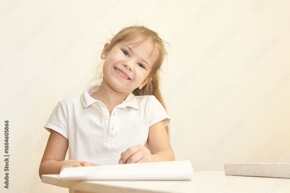 Smiling caucasian female child drawing at desk in white shirt. Smiling caucasian female child drawing at desk in white shirt.
