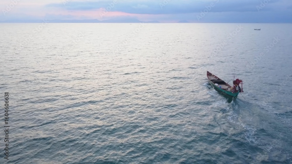 Naklejka premium Koh Tonsay, a stunning paradise in Cambodia, offers breathtaking aerial views showcasing a tranquil boat navigating calm waters as the sun rises, inviting relaxation.