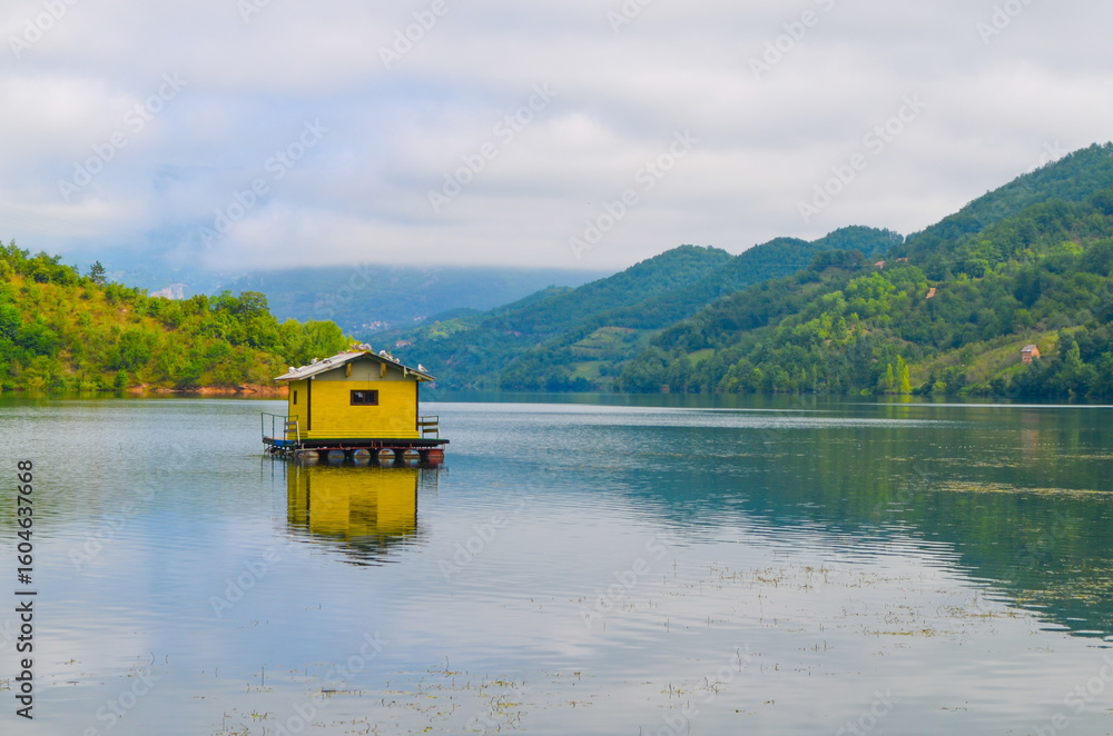 Fototapeta premium Tranquil Lakeside Cabin with Mountain Backdrop