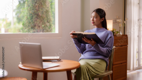Konstfotografi Asian young adult woman reads book at home by window tranquil indoor setting enj