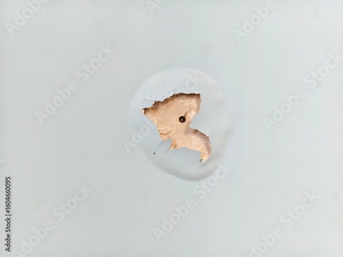 damaged walls with peeling paint and plaster and small nail or screw heads in the exposed areas