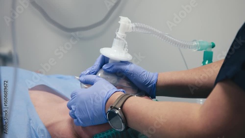 Patient receiving medical treatment with an airway management device, lying on a hospital bed, showcasing healthcare technology and patient care in a clinical environment
