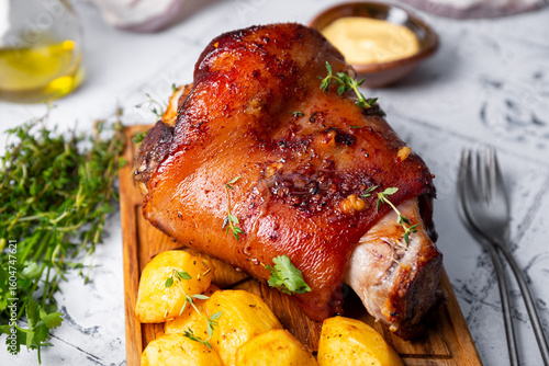 Baked pork knuckle with potatoes and cheese sauce close up