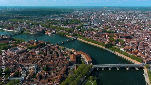 Sweeping 4K aerial of Toulouse, the Pink City, over the Garonne River with Pont Neuf, the La Grave dome and red‑brick skyline bathed in clear spring light. South France.