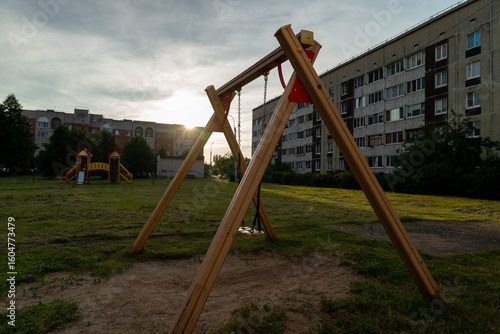 Wallpaper Mural Empty swing set stands on playground in front of apartment building at sunset Torontodigital.ca