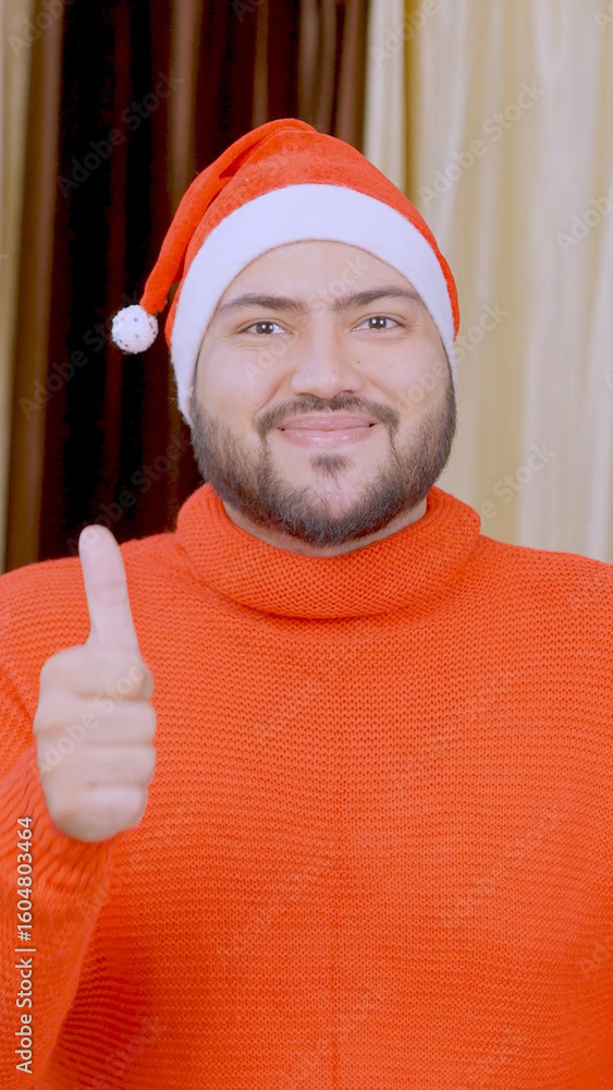 Naklejka premium Vertical Photo of Indian Man Showing Thumbs Up with Christmas Tree in background