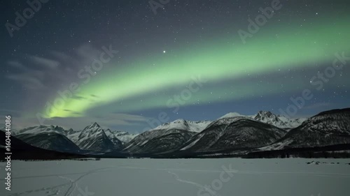 Northern lights over a snowy mountain range at night