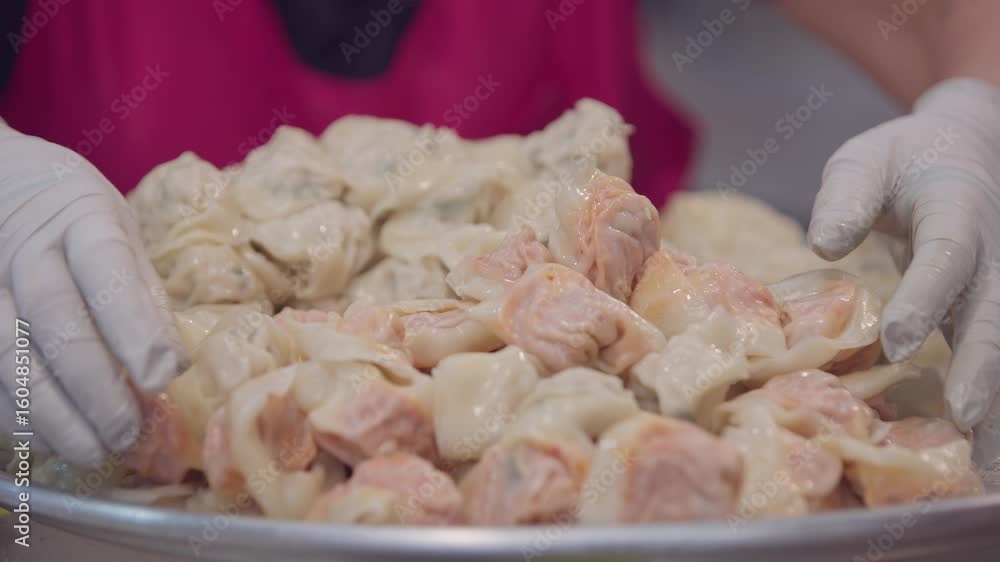 Slow motion close-up of hands shaping and preparing traditional Korean dumplings at food stall in Gwangjang Market, showing texture, ingredients and teamwork in preparation. Slow motion close-up of hands shaping and preparing traditional Korean dumplings at food stall in Gwangjang Market, showing texture, ingredients and teamwork in preparation.