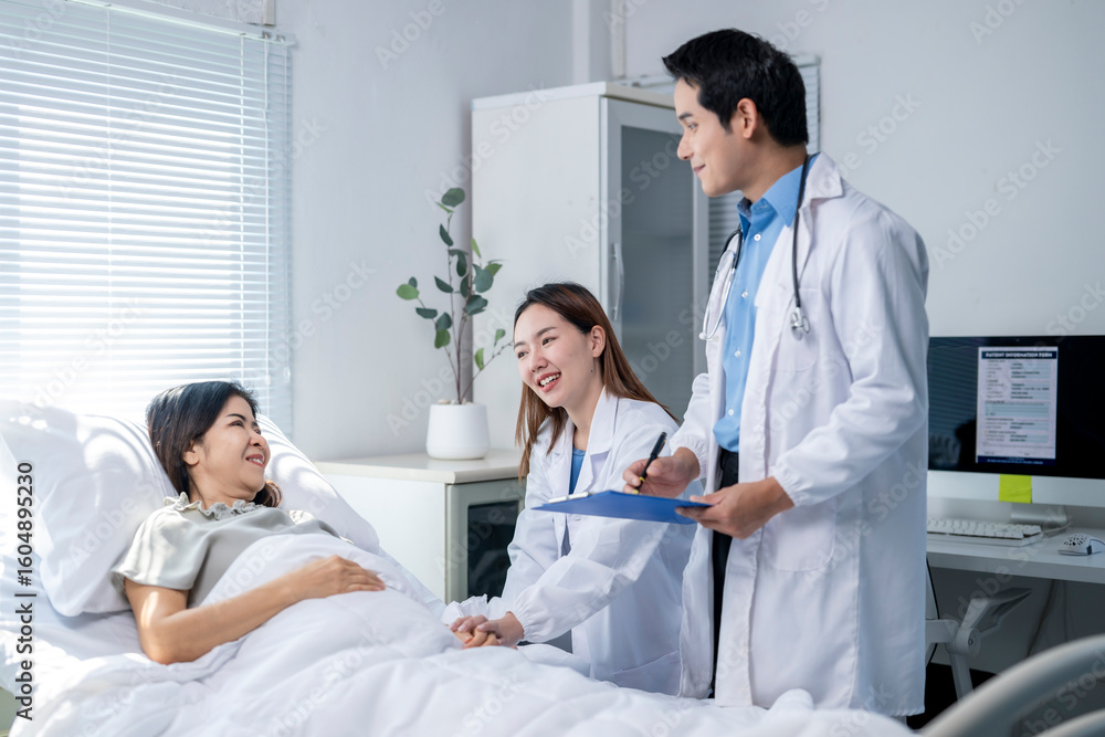 Obraz premium A woman is laying in a hospital bed with two doctors standing over her