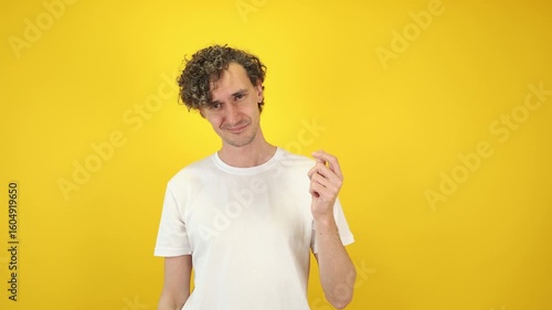 Smiling man asking money gesture on yellow studio background. Smart man smiles slyly, he has idea how earn. Profitable investments, stock market game, cryptocurrency mining. Thanks. World Savings Day