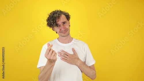 Smiling man asking money gesture on yellow studio background. Smart man smiles slyly, he has idea how earn. Profitable investments, stock market game, cryptocurrency mining. Thanks. World Savings Day