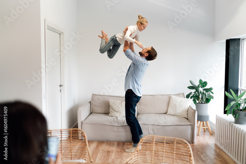 Father lifts daughter high in the air, capturing joyful parenting and digital detox moments that reflect emotional balance within connected family life.