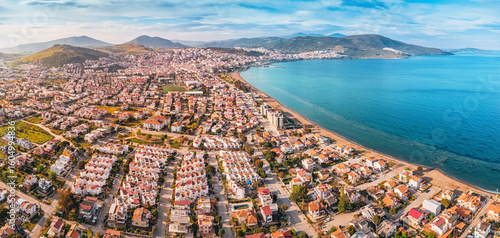 Fototapeta Naklejka Na Ścianę i Meble -  Drone capturing the cityscape of Dikili, its residential neighborhoods, the Aegean Sea, and the surrounding mountains in Turkiye