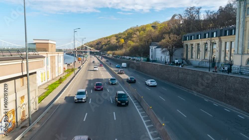 Kyiv, Ukraine - 04.13.2025: Timelapse. A highway in Kyiv with heavy car traffic on a sunny day with beautiful blue sky and clouds over the city