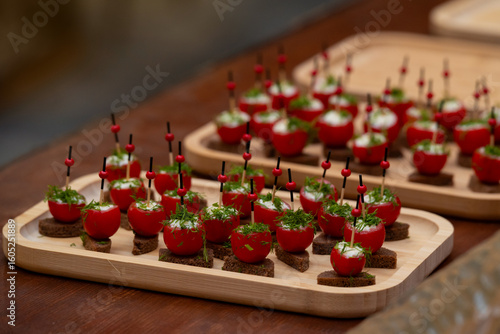 Принти на полотні Delicious appetizer bites with cherry tomatoes stuffed with creamy filling, topped with herbs, served on rye bread squares and skewered with decorative sticks