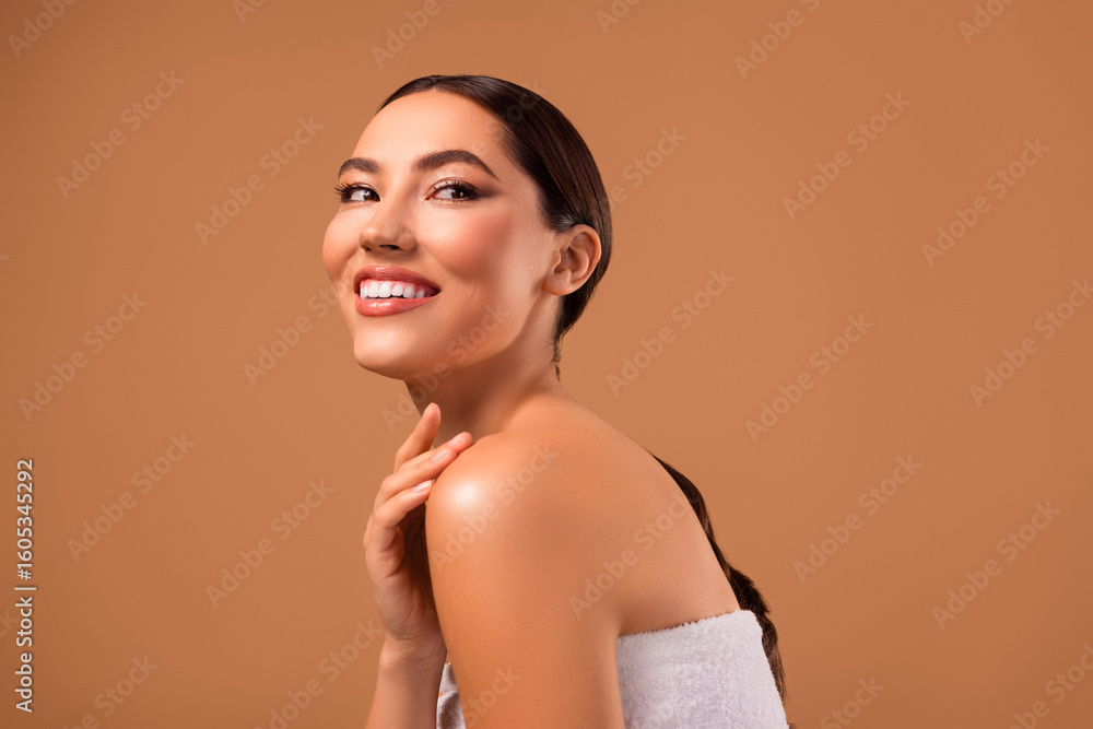 Obraz premium Smiling young woman with flawless skin and elegant hairstyle posing in a stylish spa-themed setting.