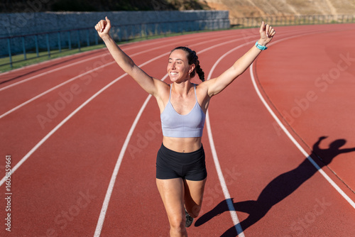 Young female athlete celebrating winning running race on track