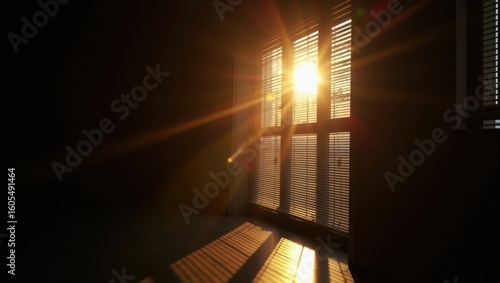 Sunlight streaming through window blinds creating shadows in a dimly lit room with dark walls
