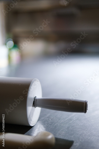 Rolling pin resting on stainless steel countertop in pizza restaurant kitchen