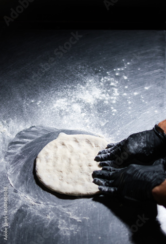 Chef preparing pizza dough on floured surface in restaurant kitchen