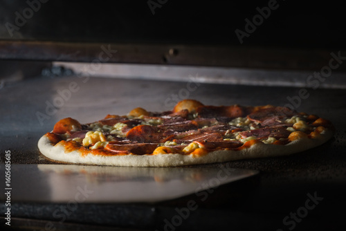Delicious pizza baking in professional oven with pepperoni and cheese