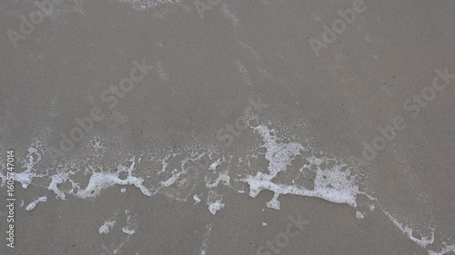 wet sandy beach by the sea with foam from the waves