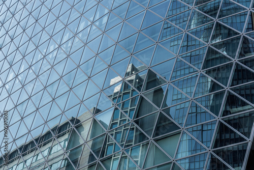 Fotografija A grid of triangular glass panels creates a modern facade, reflecting nearby buildings