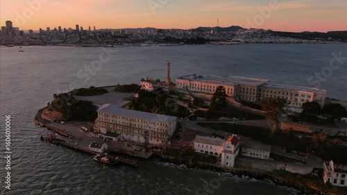 Aerial view of Alcatraz Island, a former prison, at sunset in San Francisco, California, USA. The image captures the iconic landmark and city skyline.