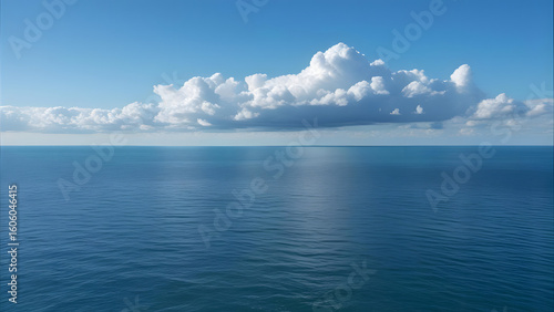 Vast expanse of calm, blue ocean water under a bright, puffy cloud formation.