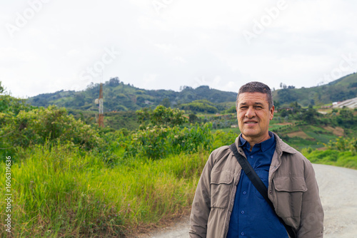 Man standing on rural path surrounded by lush landscape and communications tower in Colombian countryside. Portrait.
