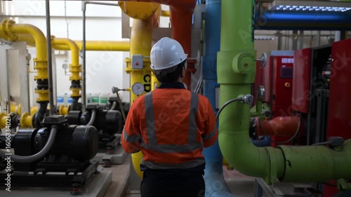 Asian engineer wearing glasses working in the boiler room,maintenance checking technical data of heating system equipment,Thailand people
