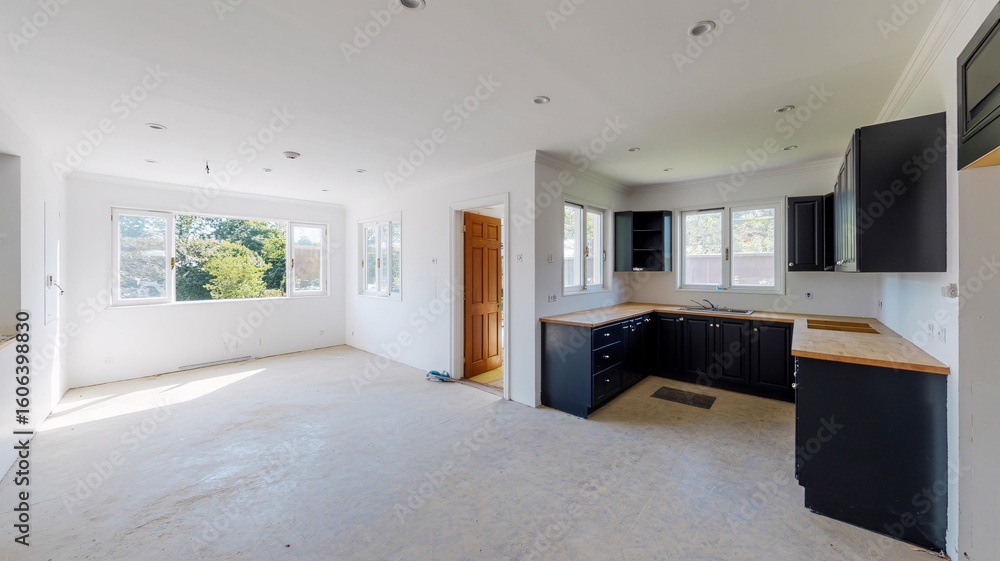 Fototapeta premium Modern open concept kitchen design with black cabinets and white walls in a bright and spacious home interior
