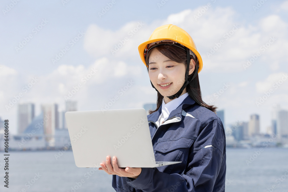 ノートパソコンを使う作業服を着た若い女性 ノートパソコンを使う作業服を着た若い女性