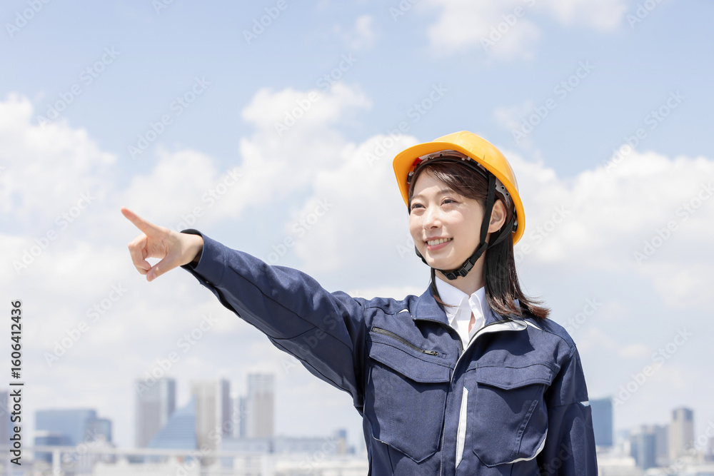 指差しをする作業服を着た若い女性 指差しをする作業服を着た若い女性