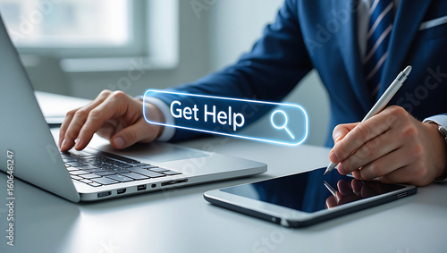 A person using a laptop and a tablet with get help search bar and a stylus in an office setting