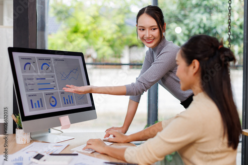 Foto Asian project manager uses laptop displayed data analysis while professional business team brainstorming marketing idea at business meeting