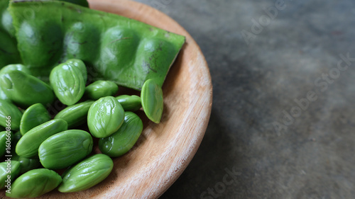 Fotografie Fresh petai or stink beans in wooden plate on cement background