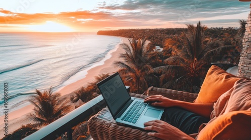 Laptop on balcony overlooking beach at sunrise