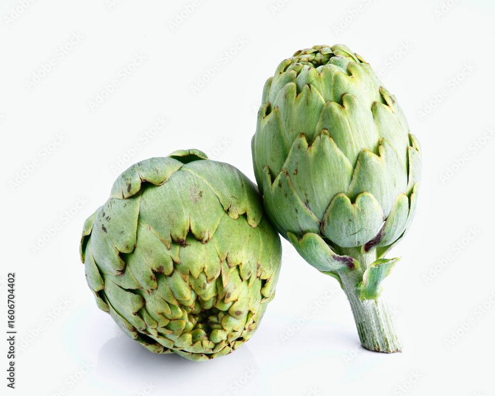 Fototapeta premium Two fresh artichokes resting on white reflective surface