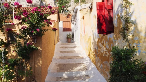 Wallpaper Mural Stone stairway in Anafiotika, Athens, Greece, leads between weathered yellow and white houses. Red shutters, pink bougainvillea, greenery add color. No people. Sunny day with cozy, old town atmosphere Torontodigital.ca