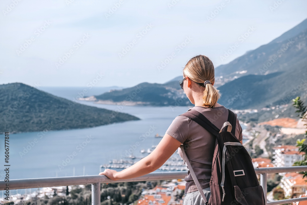 Fototapeta premium Woman enjoys solo travel, retreat and mindfulness sea, mountain, coast, marina; exploring slow adventure, freedom, calm, awareness, soft experience, relaxation, selfcare, youth lifestyle.