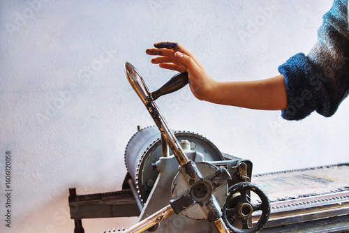 Foto Artist hand operating manual printing press in traditional print studio
