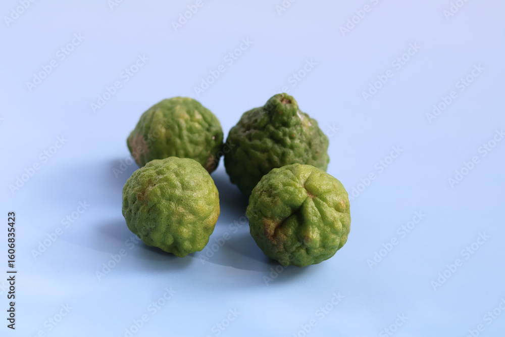 Fototapeta premium Fresh kafir limes display vibrant green color and unique bumpy texture, showcasing their natural beauty. These limes are often used in culinary dishes and traditional remedies