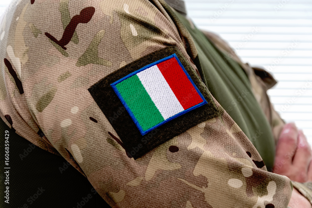 Obraz premium A man in an army uniform with an Italian flag on his sleeve and army badges.