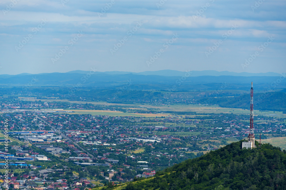 Obraz premium panoramic view from above of the streets of Piatra Neamt, Romania, and the hill with the communication tower, urban architecture, urban landscape