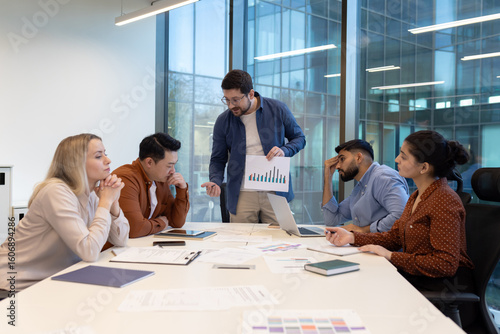 An angry boss confronts colleagues during a tense meeting in a modern office setting, presenting charts