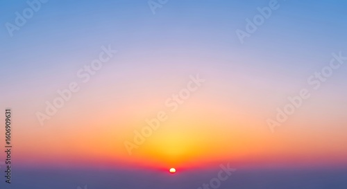 A vibrant sunset with a gradient sky transitioning from blue to orange and a visible sun disk at horizon