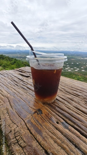 Refreshing iced coffee on wooden table outdoors.