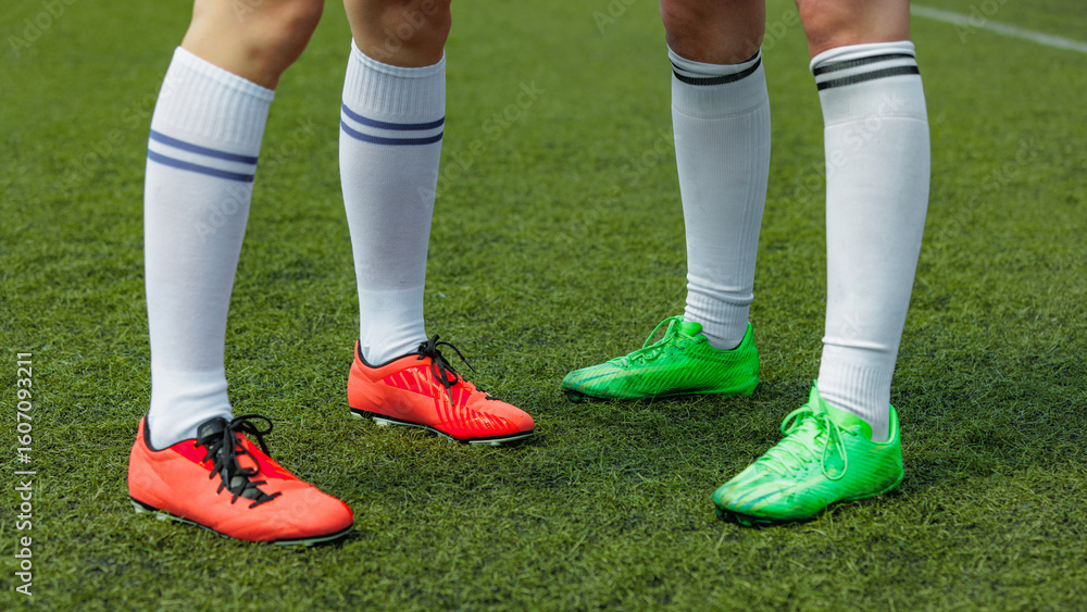 Fototapeta premium Women soccer athletes donned vibrant cleats on lush green field. Concept of pre-game energy, color-focused asset for gear and sportswear brand visuals.